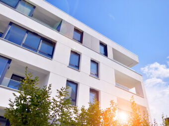 building with blue sky trees background scaled