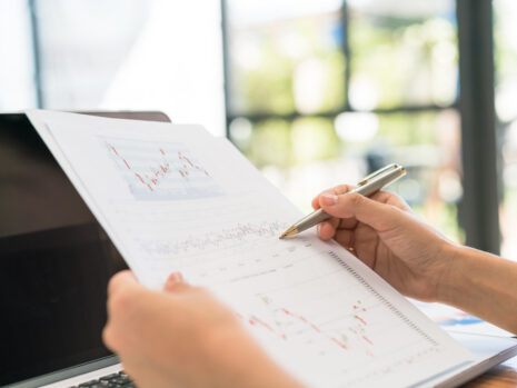 business woman hand with financial charts laptop table
