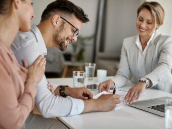 happy man his wife having meeting with financial advisor signing agreement office scaled