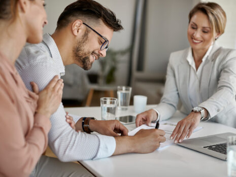 happy man his wife having meeting with financial advisor signing agreement office scaled