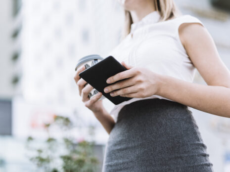 low angle view businesswoman holding smartphone disposable coffee cup outdoors scaled