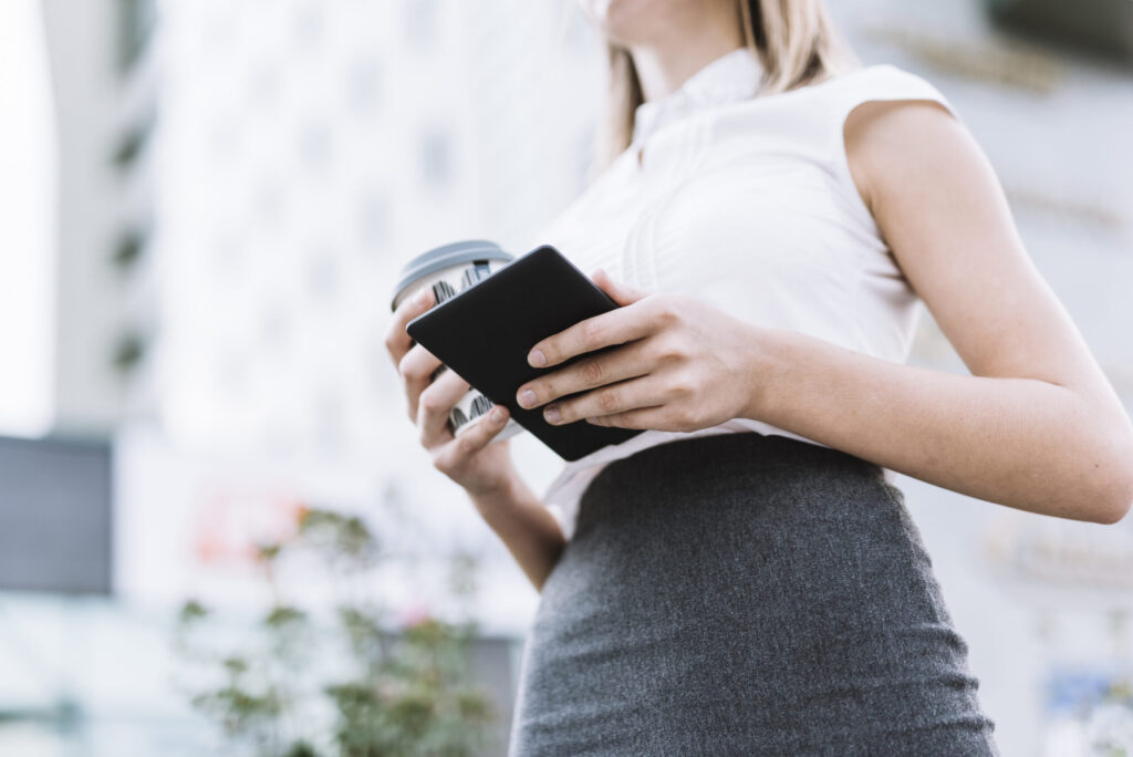 low angle view businesswoman holding smartphone disposable coffee cup outdoors scaled