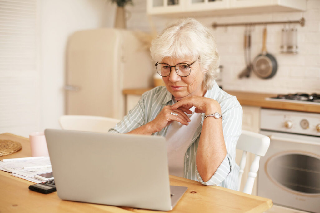 Inflation hemmt Kapitalaufbau fürs Alter 1 modern technology old people retirement gray haired female pensioner glasses filling loan application form online sitting front laptop reading information with serious focused look scaled