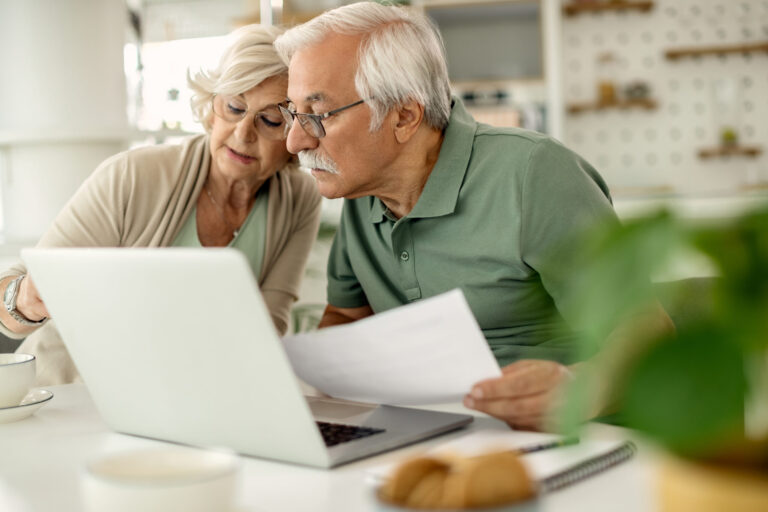 senior couple analyzing their savings while going through home finances scaled