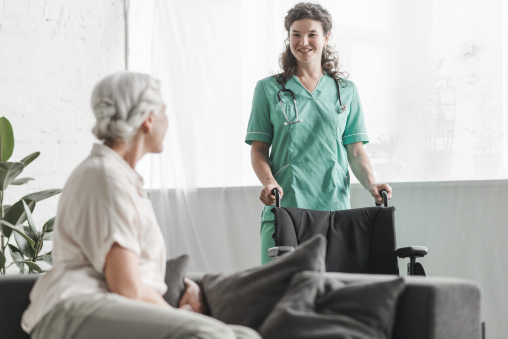 senior woman looking smiling female nurse with wheelchair scaled