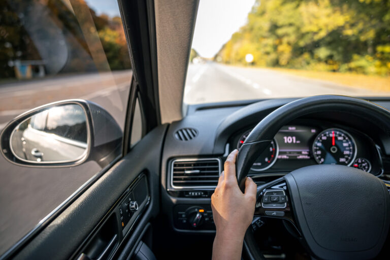 woman drivers hands steering wheel inside car scaled